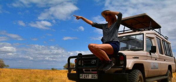 wijzende vrouw op de voorkant van een stoere 4x4 op huwelijksreis in tanzania