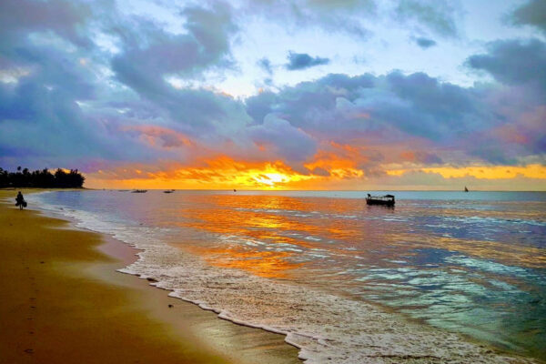 oranje gekleurde zee en wolken afgewisseld met blauwe wolken bij Pangani tijdens een zonsondergang