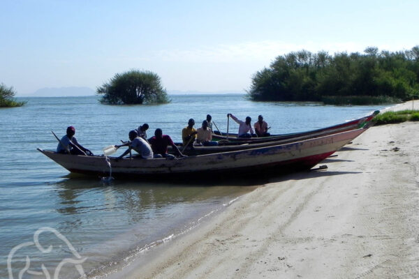 op het strand bij lake victoria met twee boten en vissers daarin die zich klaarmaken het meer op te gaan