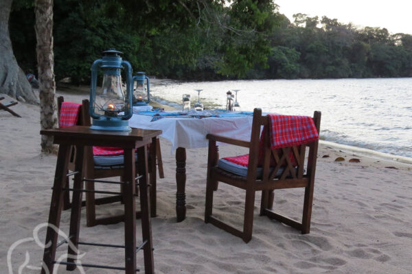 op het strand een gedekte tafel met stoelen klaar voor een romantisch diner aan het het lake victoria