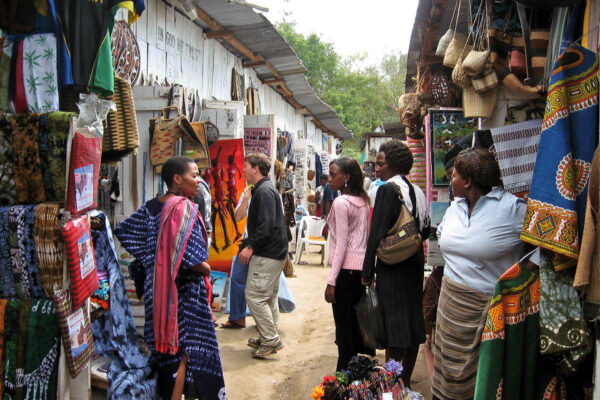 nauw straatje in Arusha met souvenirs winkeltjes en vier vrouwen die met elkaar praten