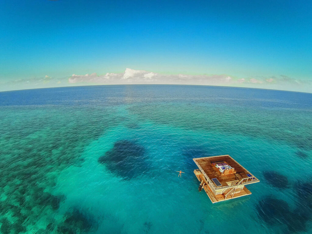 azuurblauwe oceaan met een persoon die zwemt bij de onderwaterkamer van manta resort pemba tanzania