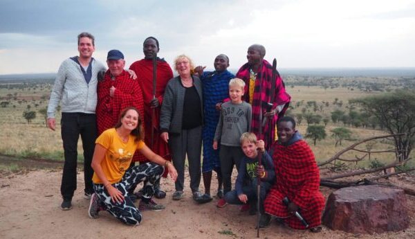 famile met opa oma zoon en schoondochter en kleinkinderen met dire masai mannen tijdens een bezoek aan de masai in tanzania