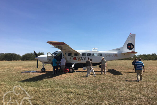 kleine vliegtuigjes in Tanzania, airstrip met een vliegtuigje en verschillende mensen die net zijn aangekomen en een Fly-in safari naar de Serengeti hebben