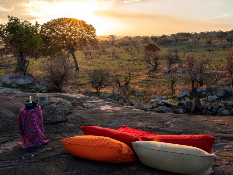 champagne en kleedjes en een uitzicht over de serengeti waar de zon ondergaat