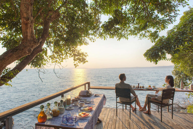 zittend jong stel aan het ontbijt uitkijken over lake victoria romantisch rubondo eiland camp tanzania huwelijksreis