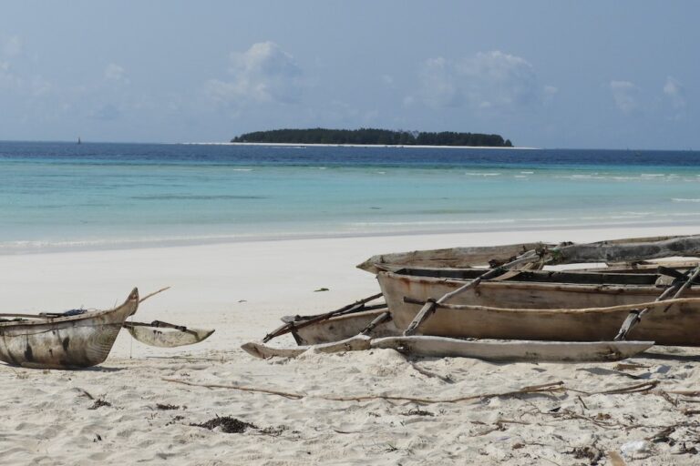 uitzicht over een azuurblauwezee op Zanzibar met bootjes op de voor grond