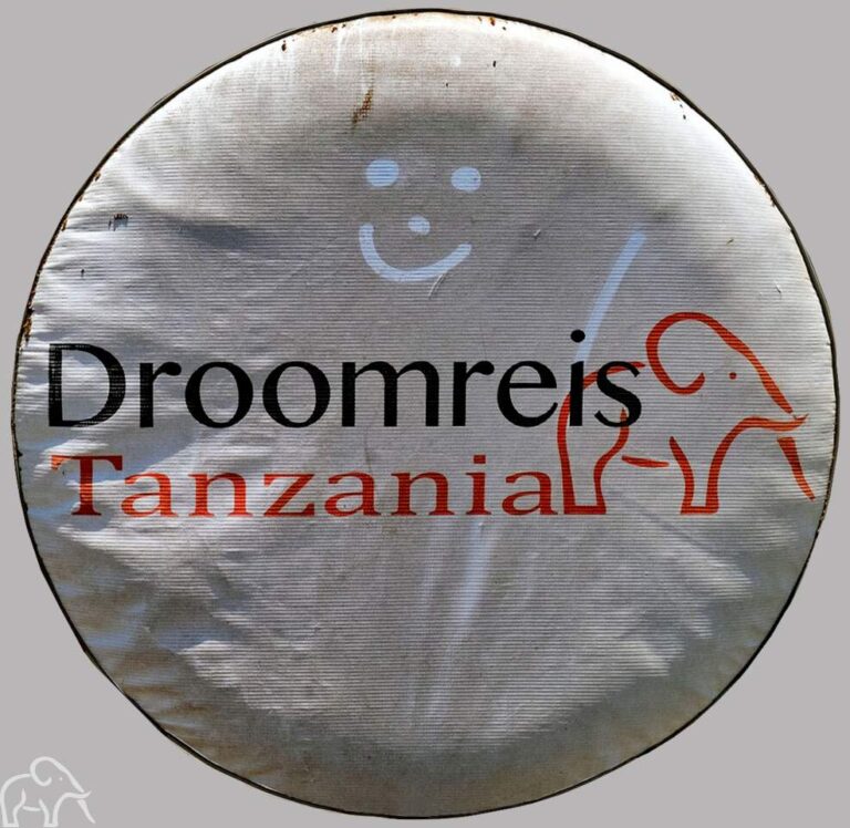 Uitgelicht de hoes van Droomreis Tanzania om een autoband op de safariauto van Droomreis Tanzania. Op de vieze hoes is een smiley getekend door de gasten. Review Droomreis Tanzania