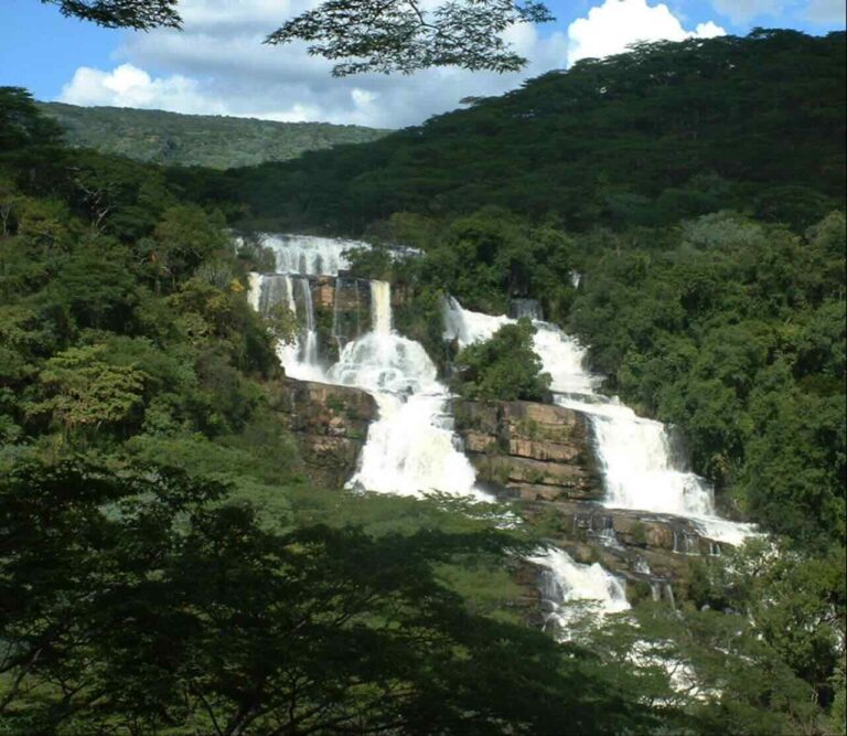 Indrukwekkende waterval die over rotsen gaat met daarnaast allemaal bossen