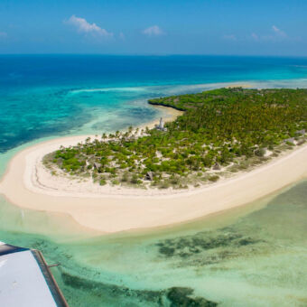 eiland vanuit een kleinvliegtuigje kijken we op het ovaalvormig eiland Fanjove met groene bosjes met witte strandenomringt door een azuurblauwe zee