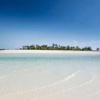 hagelwitte stranden Spierwit strand met kabbelende zee en op de achtergrond wat groene struiken tegeneen staalblauwe lucht op Fanjove eiland de plek voor een huwelijksreis