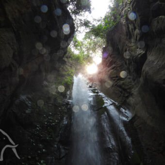 waterval in Gombe van onderaf kijk je tussen de rotsen door naar de waterval in Gombe National Park Tanzania