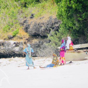 locals 4 vrouwen in traditioneel felgekleurde kleding op het strand bij Pemba Tanzania