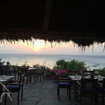 diner met uitzicht terras met gedekte tafels bij een ondergaande zon met uitzicht op zee