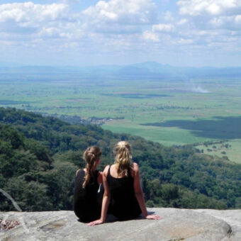 vergezichten twee jonge meiden zittend op een rots uitkijkend over een vallei bij Udzungwa mountains