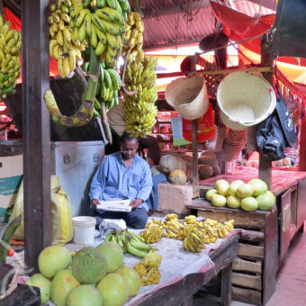 Stonetown verse meloenen, bananen en manden met zittende lezende man op de Darjani markt Stone Town zanzibar