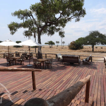 uitzicht over de plains van het terras met tafels en parasollen een uitzicht over de goud gele vlaktes van Katavi