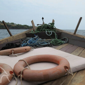 dhow vanaf de voorkant van de dhow de reddingsbanden en een klein stukje van het anker en uitzicht op de oever van Lake Tanganyika