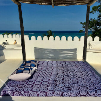 dakterras met zeezicht wit dakterras met twee persoons ligbed met afdakdak kijkend over de indische oceaan op Zanzibar