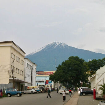 mount Meru weg door arusha netgebouwen linksen rechts en wat bomen en op de achtergrond Mount Meru met witte top