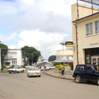 straatbeeld centrum van Arusha bij een rotonde met gebouwen aan de kant en auto's