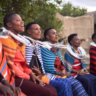 Zingende en vrolijk kijkende kleurrijke Masai vrouwen