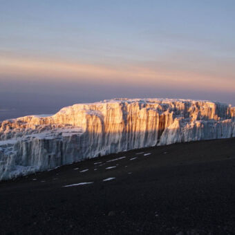 top uitzicht van dichtbij van een zonsopkomst op de witte met rood gekleurde sneeuw op de top van de Kilimanjaro