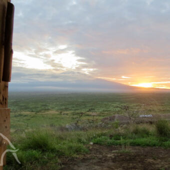 vanuit de deuropening zonsopkomst met links daarvan de kilimanjaro