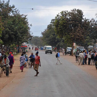 weg metsel mensenos en langs de weg met in de verte een safari auto in Mto-wa-Mbu