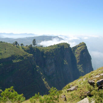 hoge rotsen groen bergen met diepe kloven en op de top heel ver weg een klein groepje olifanten op de top van bij Usumbara Mountains