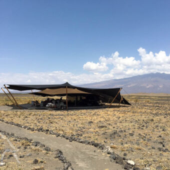 Lake Natron camp in maandmanschap achtige omgeving bij Lake Natron een open tent met groot schaduwdoek wat dienst doet als restaurant voor een lodge