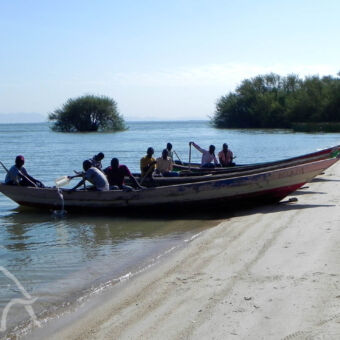 kanotocht op het strand bij lake victoria met twee boten en vissers daarin die zich klaarmaken het meer op te gaan