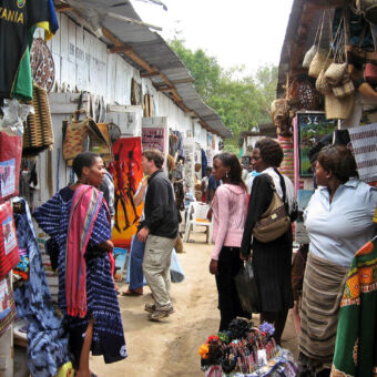 souvenirs nauw straatje in Arusha met souvenirs winkeltjes en vier vrouwen die met elkaar praten