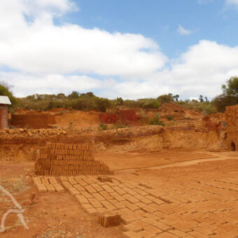 steenfabriek vlakbij de het dorp karatu stenen die liggen te drogen met daarachter een steenroven om stenen te bakken