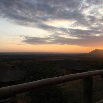 bij zonsondergang op het terras van een lodge uitzicht over de serengeti