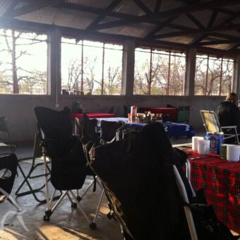 eetruimte typische tanzaniaanse eetruimte op een camping met een stenen gebouw dak van aluminium platen en de zijkanten half open met gaas. In de ruimte meerdere tafels met stoelen