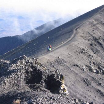 op naar de top! twee mensen die over de zwarte smalle rim naar de top lopen van Mount Menu tanzania