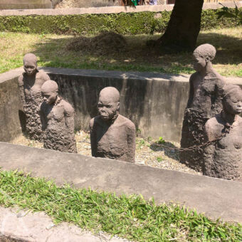 monument bij het slavenmuseum slavernij monument open graf met half uitstekend staande stenen mensen met kettingen om hun nek museum zanzibar tanzania