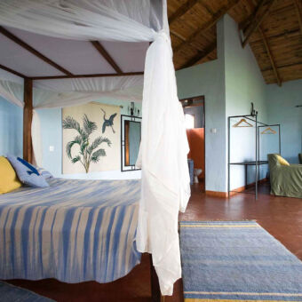 ruime kamer ruime kamer van tolma lodge met groot bed klamboe hoog schuin weglopend dak en een zithoek