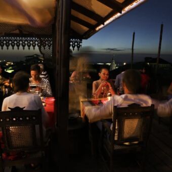 restaurant op de toproof op het dak van het Emerson spice hotel is een restaurant waar mensen aan een tafeltje zitten in de avond onder een afdak zanzibar