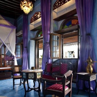 kamer Violetta hotelkamer helemaal in het blauw met een groot bed en klamboe opengelaten ramen en houten traditioneel meubilair oosterse sfeer emerson spice hotel zanzibar