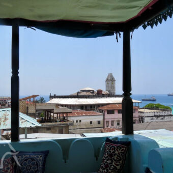 uitzicht vanaf het dakterras uop het balkon met een afdak uitkijken over stone town en de zee in het emerson spice hotel zanzibar