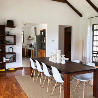 grote villa voor het hele reisgezelschap kamer in een luxe vila voor 10 personen met een houten tafel en witte stoelen in een verder witte ruimte met hout accenten