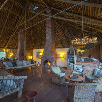 lounge lounge ruimte met rietendak en open zijkanten een haardvuur en traditionele houten banken en stoelen met lekere kussens