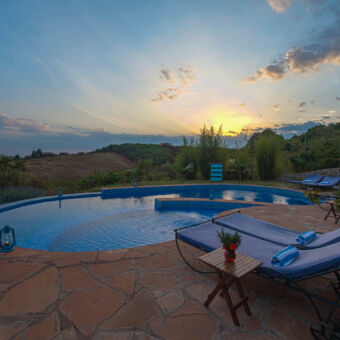 zwembad ovaal zwembad met ligbedden erom heen en een ondergaande zon bij rhotia valley lodge tanzania