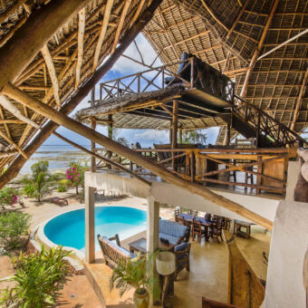 grote privé villa uitzicht op het ronde zwembad en het strand en zee vanaf de tweede verdieping van een traditioneel gebouwde familievilla met rieten dak