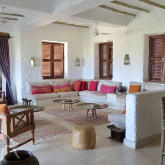 verblijf in stijl loungeruimte in oosterse stijl met een hele grote u bankkleden op de grond en spierwitte muren bij Lake Eyasi tanzania