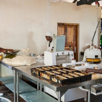 bakkerij drie mannen met witte kokskleren aan rvs tafels en bezig deeg klaar te maken om brood van te bakken