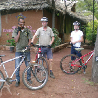 op pad met een lokale gids man en ouder kind met help op stilstaand bij hun mountainbike en een gids die belt