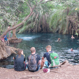 zwemmen in het warme water drie kinderen zitten aan het water van de chemka hofspring en er zwemmen ook drie mensen tijdens een wandeling